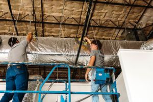 R2 technicians securing insulated ductwork overhead